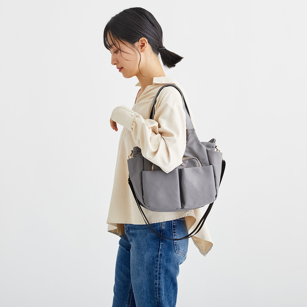 Wポケットグレーナイロン2wayハンドバッグを肩掛けする女性