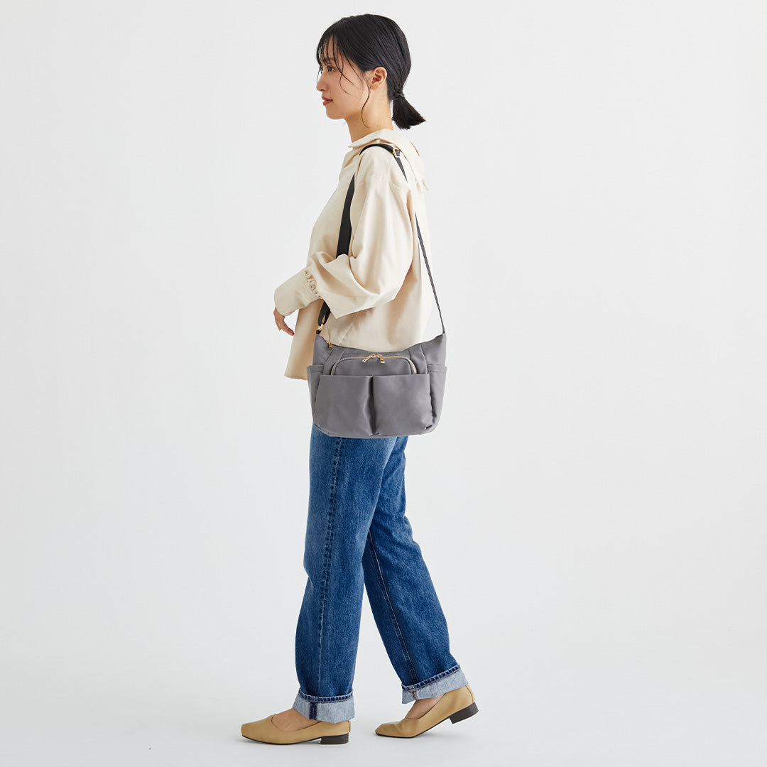 グレーナイロンショルダーバッグを肩掛けする女性