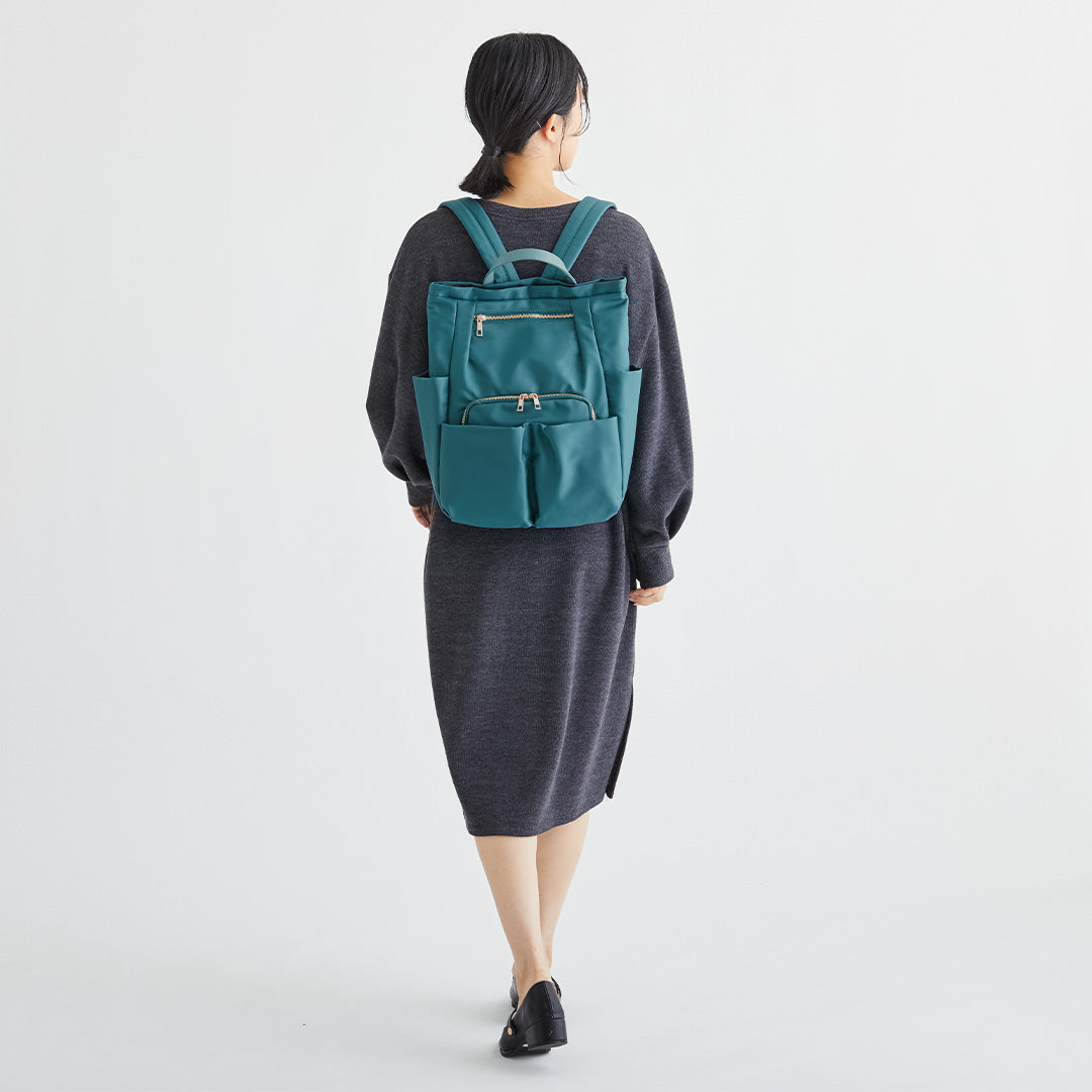 グリーンWポケットナイロンリュックを背負う女性