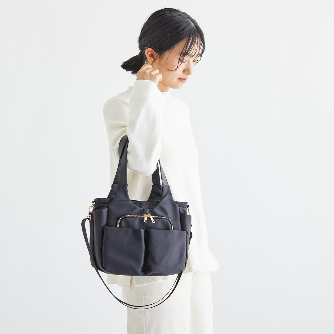 ブラックWポケットナイロン2wayハンドバッグを手に持つ女性