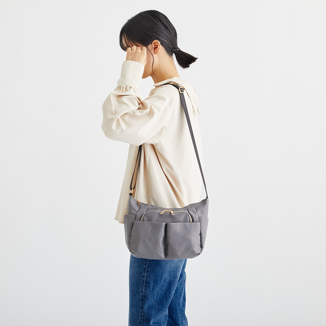 グレーナイロンショルダーバッグを肩掛けする女性