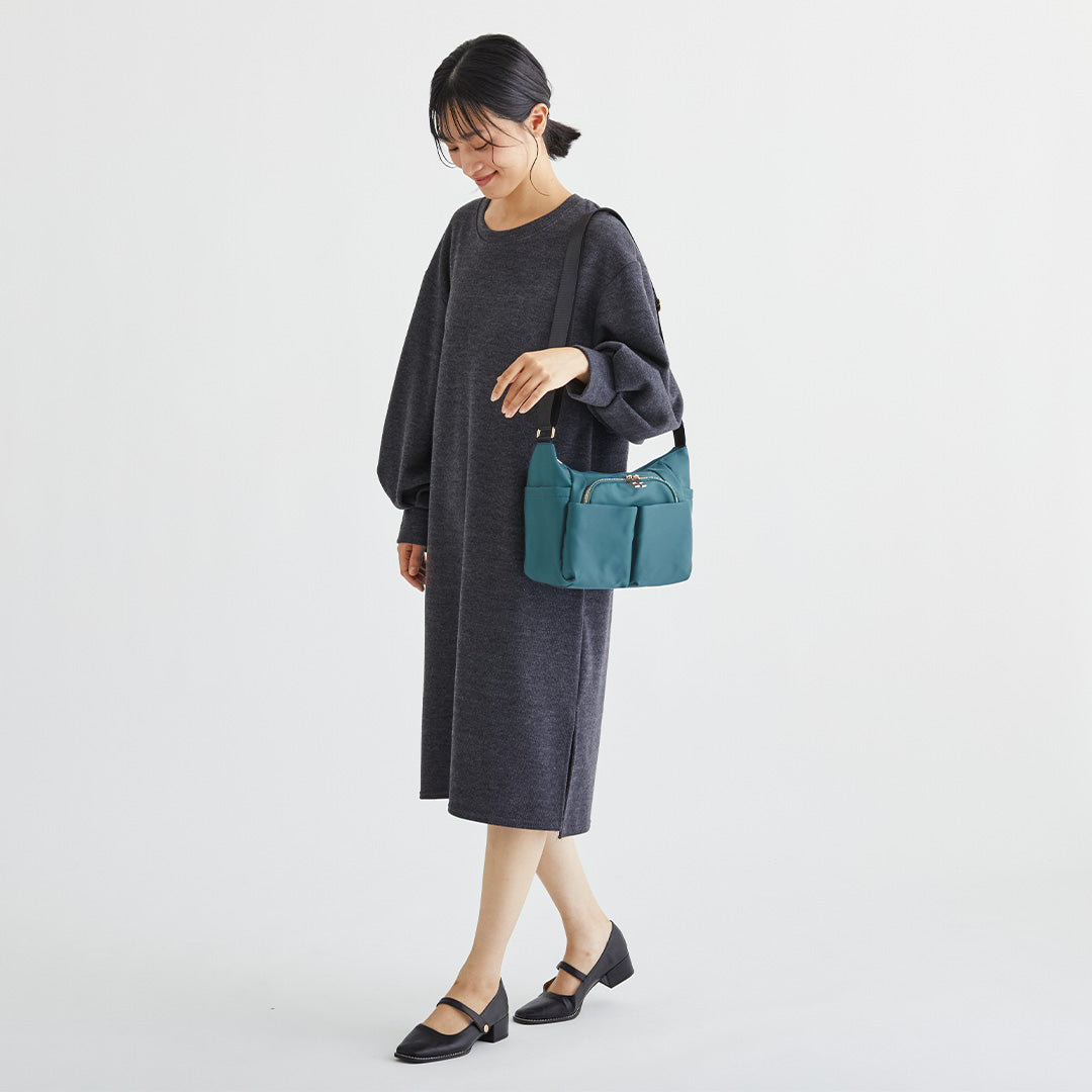 グリーンナイロンショルダーバッグを肩掛けする女性