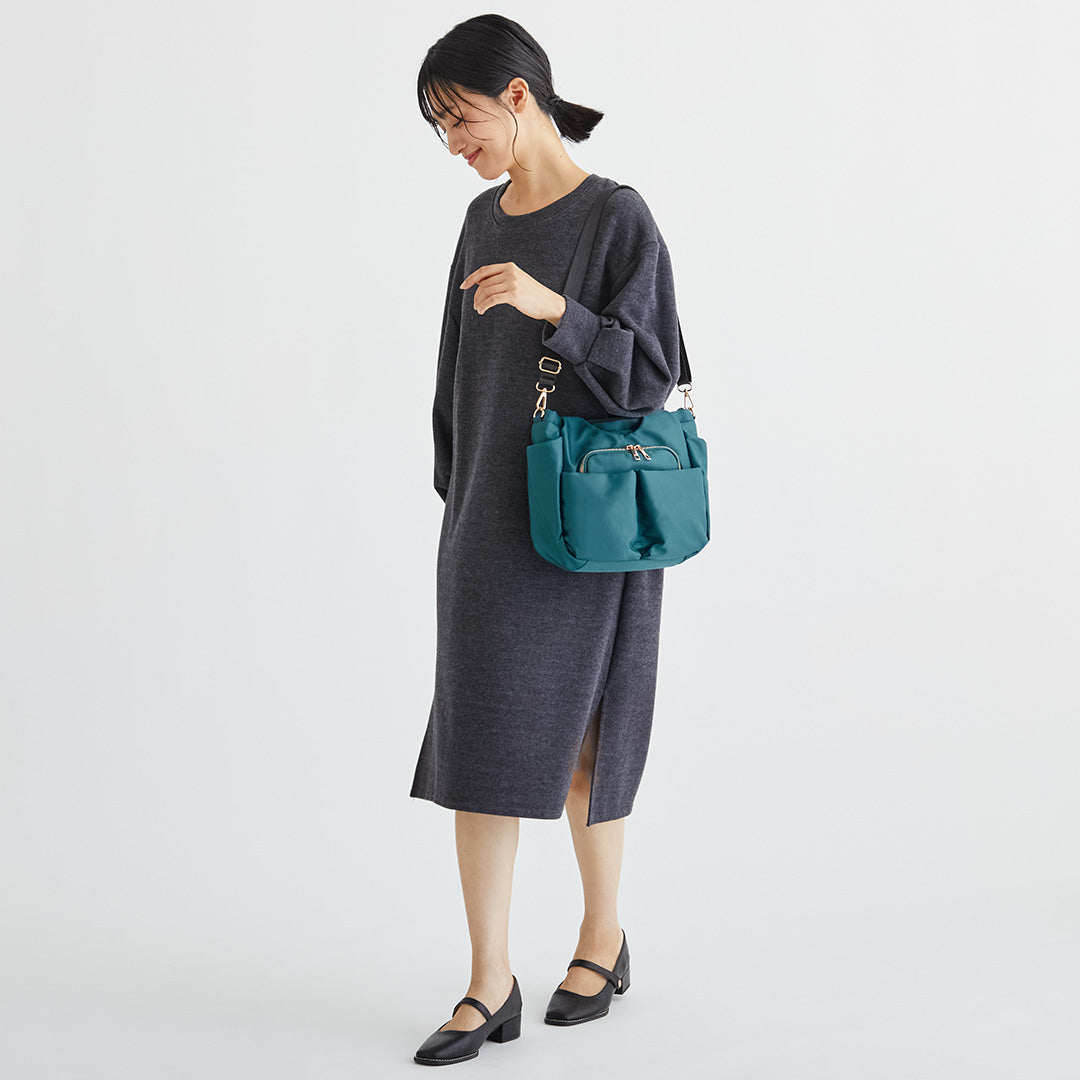 Wポケットグリーンナイロン2wayハンドバッグを肩掛けする女性