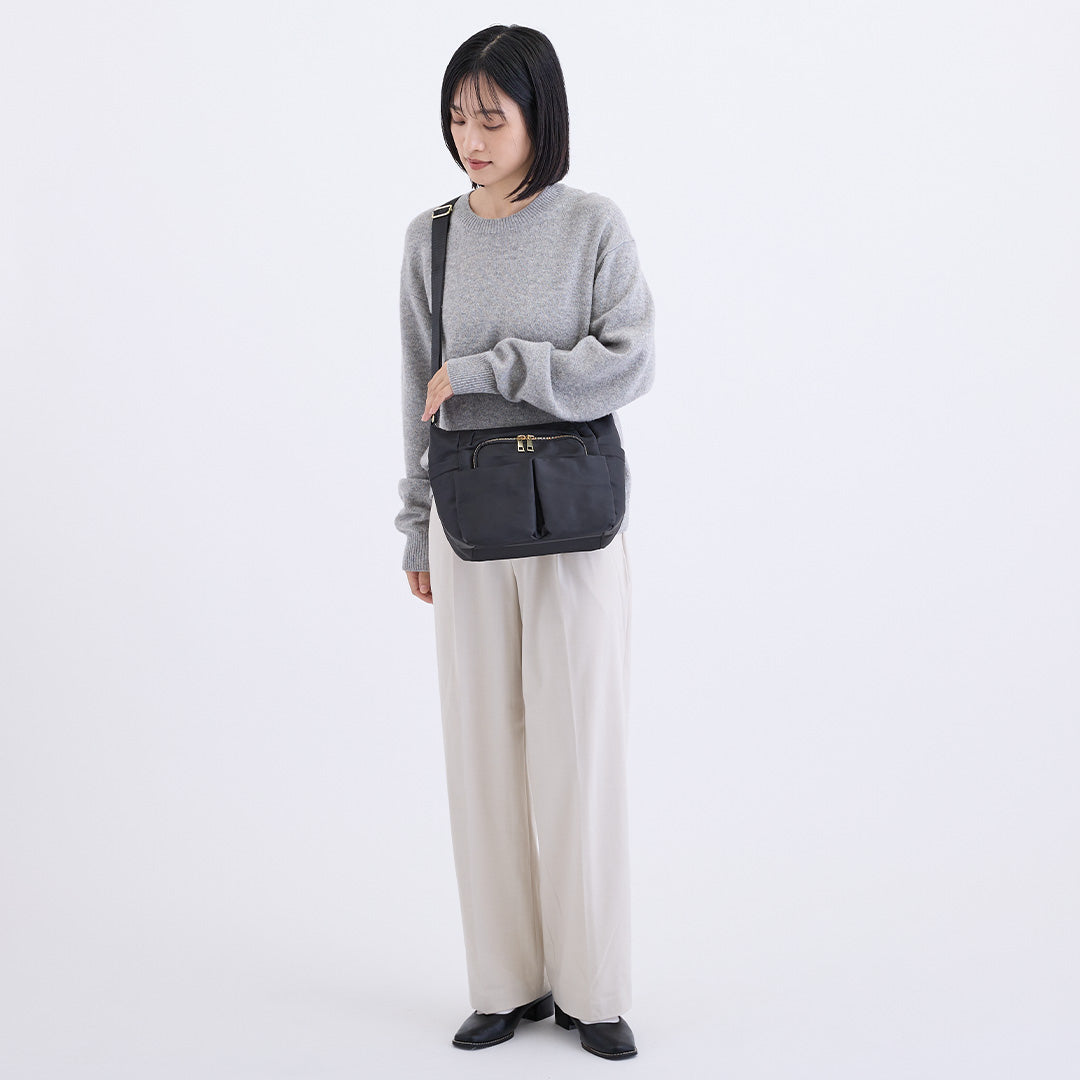 ブラックナイロンショルダーバッグを斜め掛けした女性
