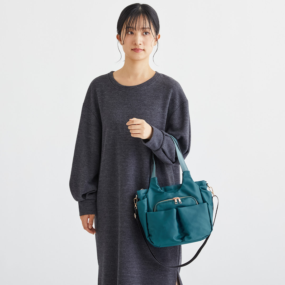 Wポケットグリーンナイロン2wayハンドバッグを手に持つ女性