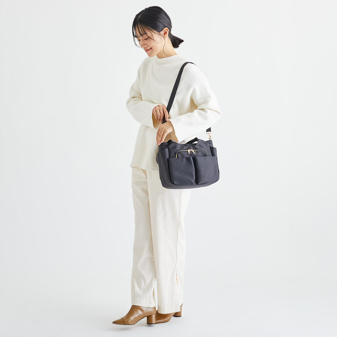 ブラックWポケットナイロン2wayハンドバッグを肩掛けする女性