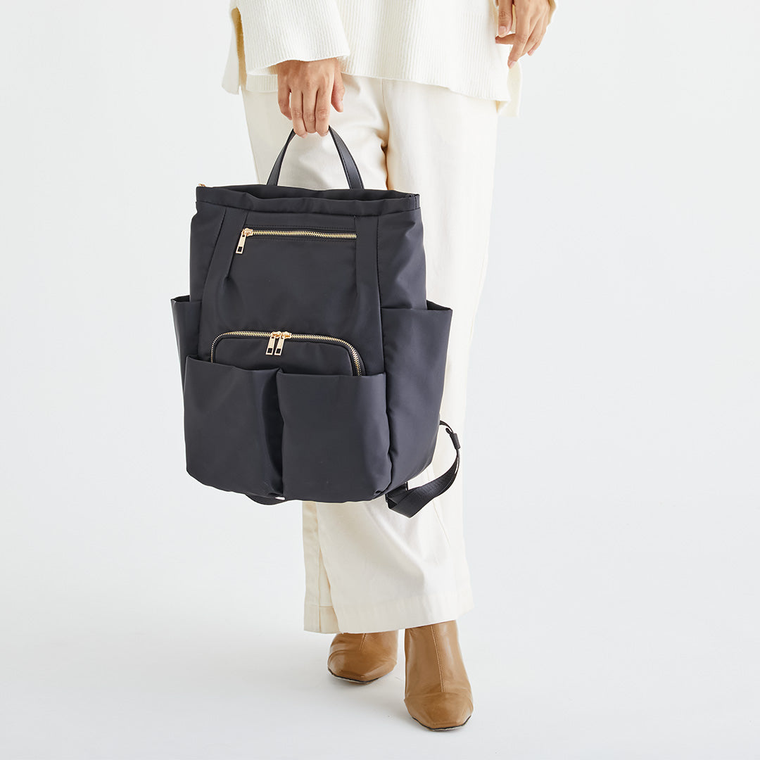 ブラックWポケットナイロンリュックを手に持つ女性