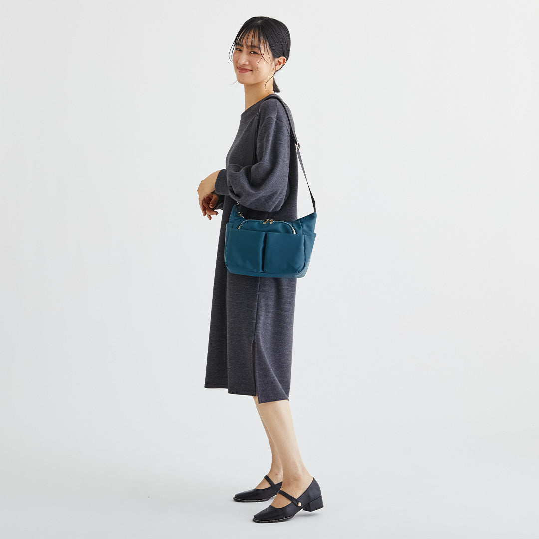 グリーンナイロンショルダーバッグを肩掛けする女性