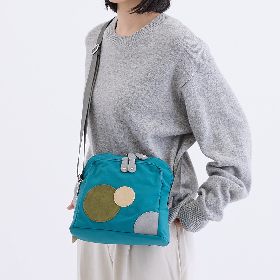 ブルーのナイロンショルダーバッグを肩にかけた女性