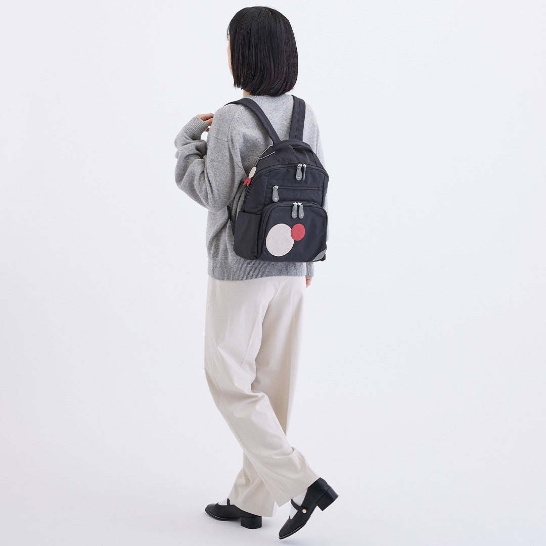 ナイロン丸モチーフリュック ブラック グレーのニットと白いパンツを合わせた着用イメージ