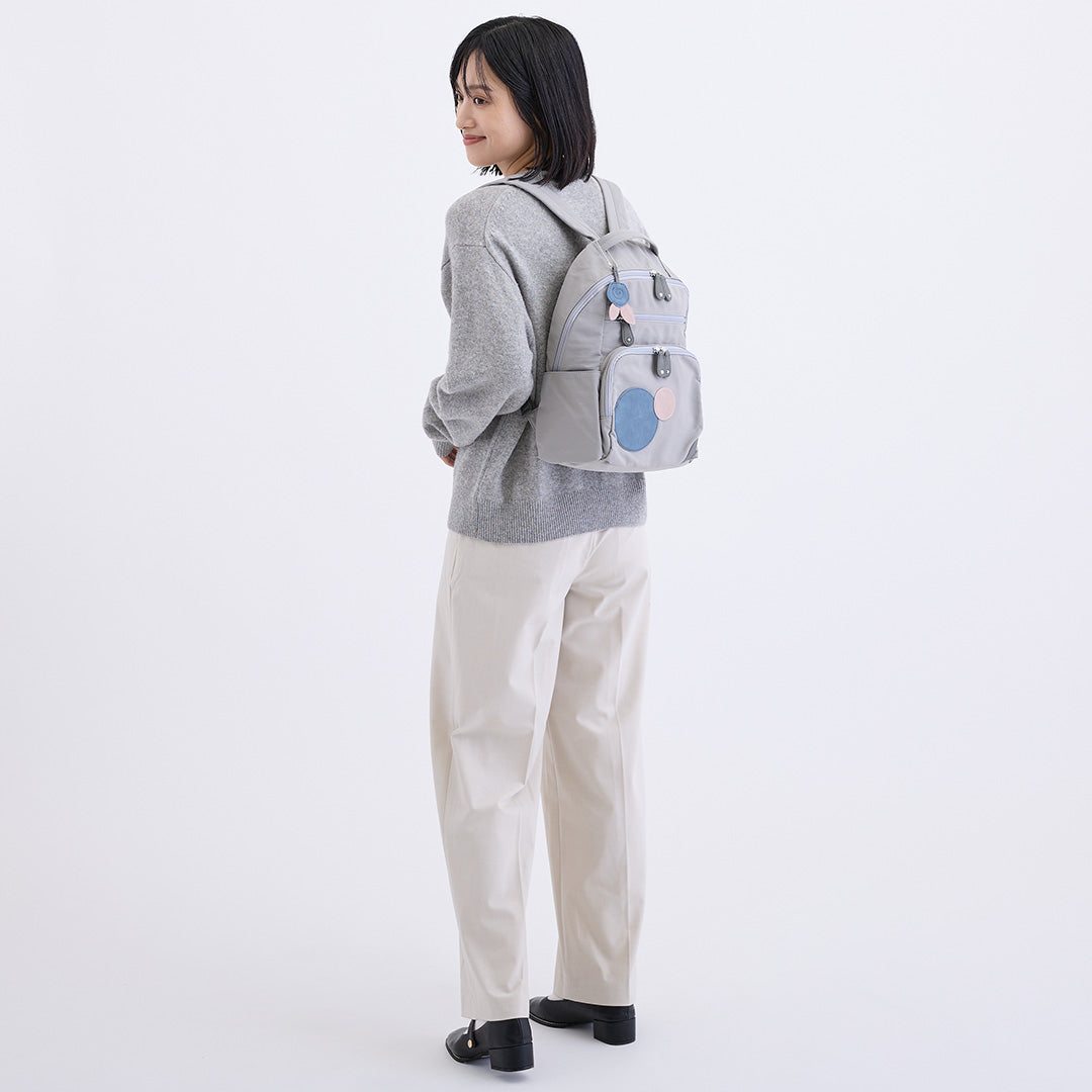 ナイロン丸モチーフリュック グレー グレーのニットと白いパンツを合わせた着用イメージ