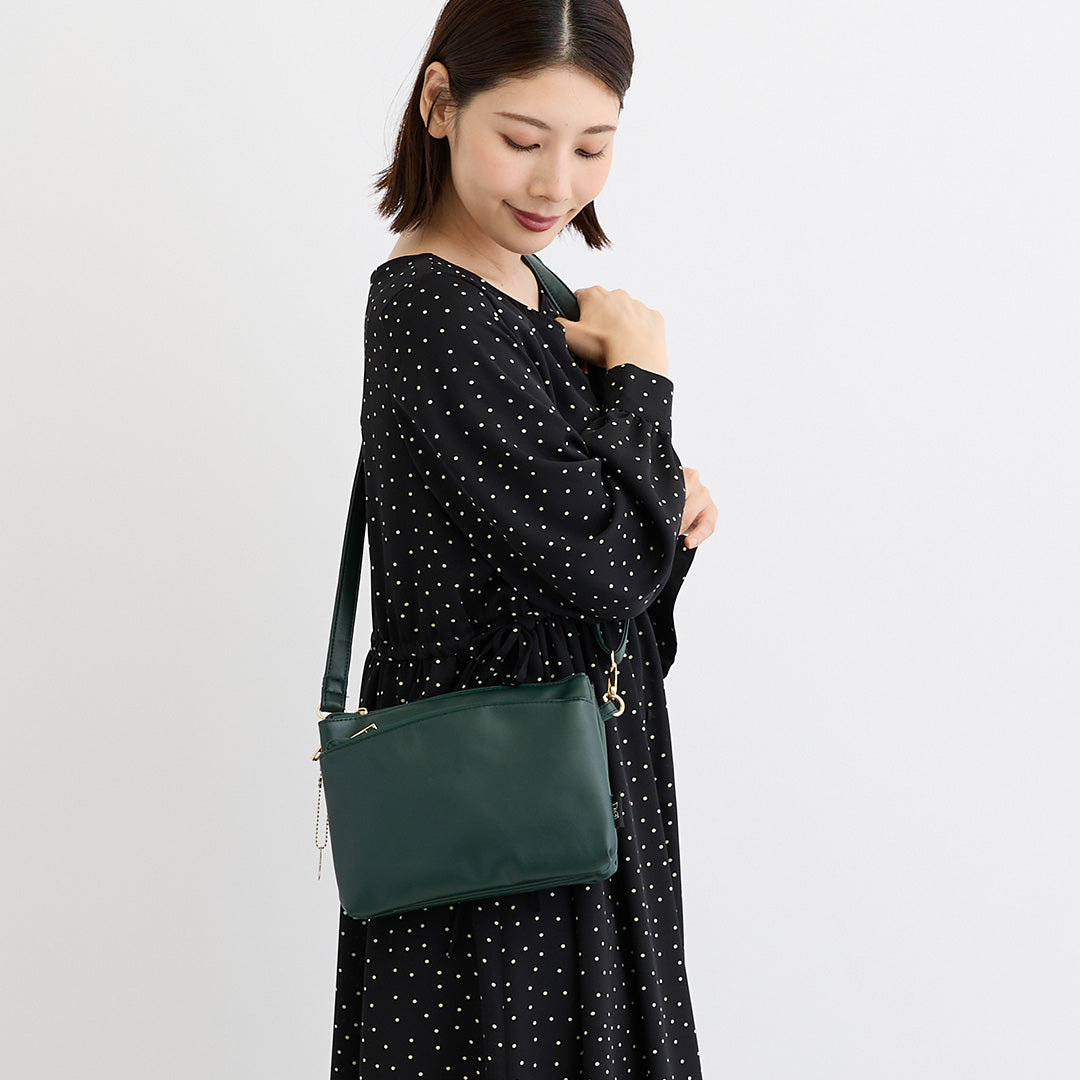 グリーン合皮ショルダーバッグを肩掛けする女性
