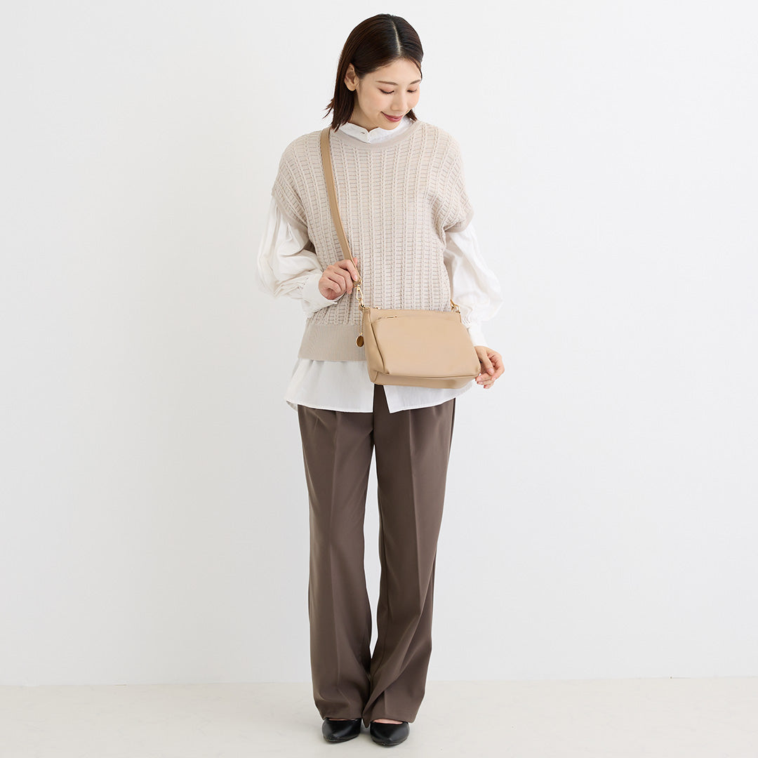 ベージュの合皮ショルダーバッグを肩掛けした女性