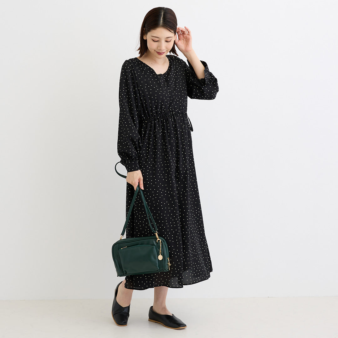 グリーンの合皮ショルダーバッグを手に持つ女性