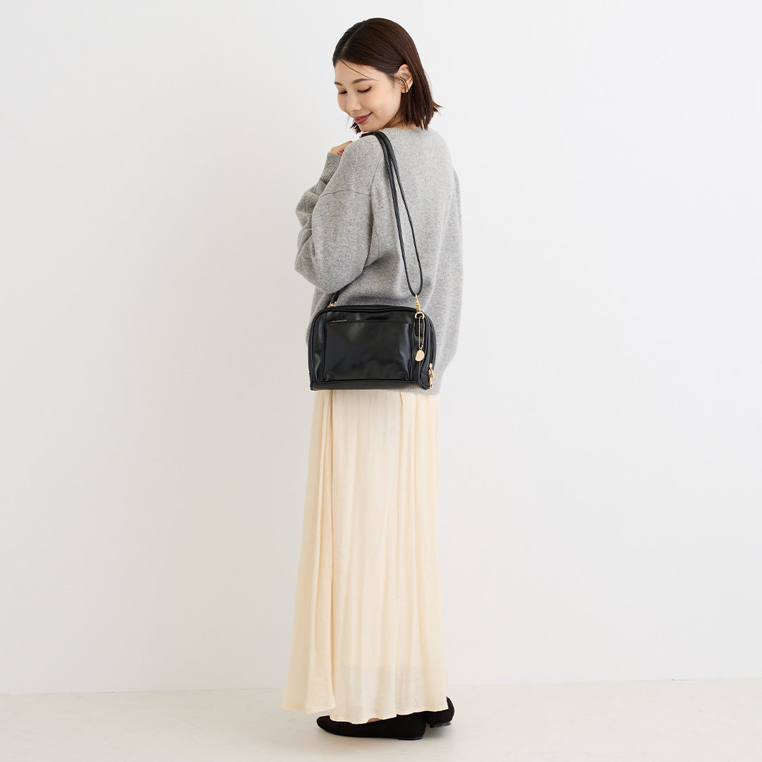 ブラックの合皮ショルダーバッグを肩掛けした女性