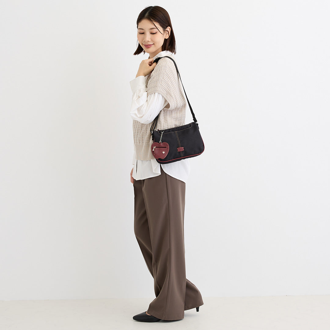 シワナイロンリンゴチャーム付きショルダーバッグミニ ブラック×レッド を肩掛けした女性の着用イメージ