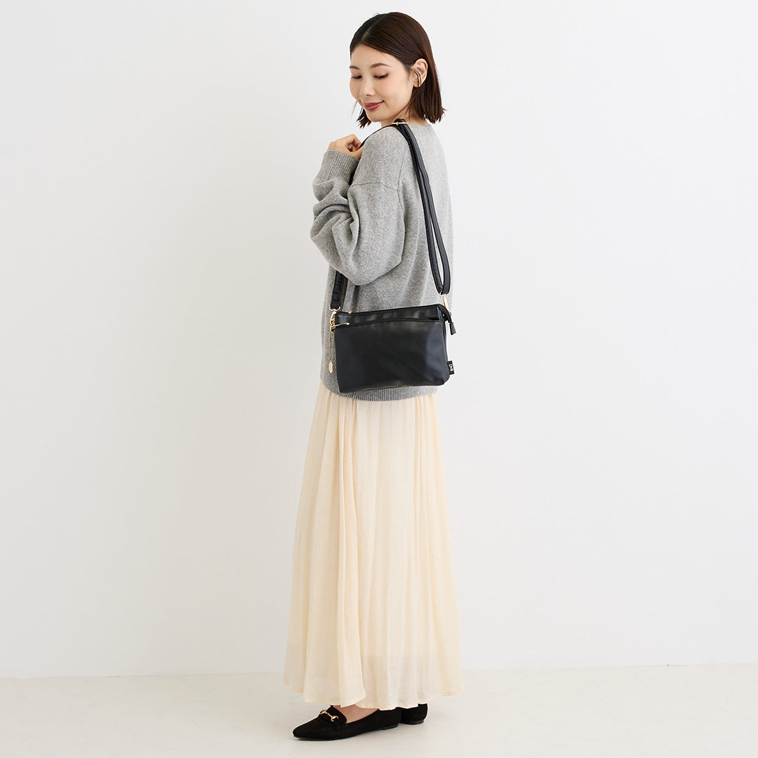 ブラック合皮ショルダーバッグを肩掛けする女性