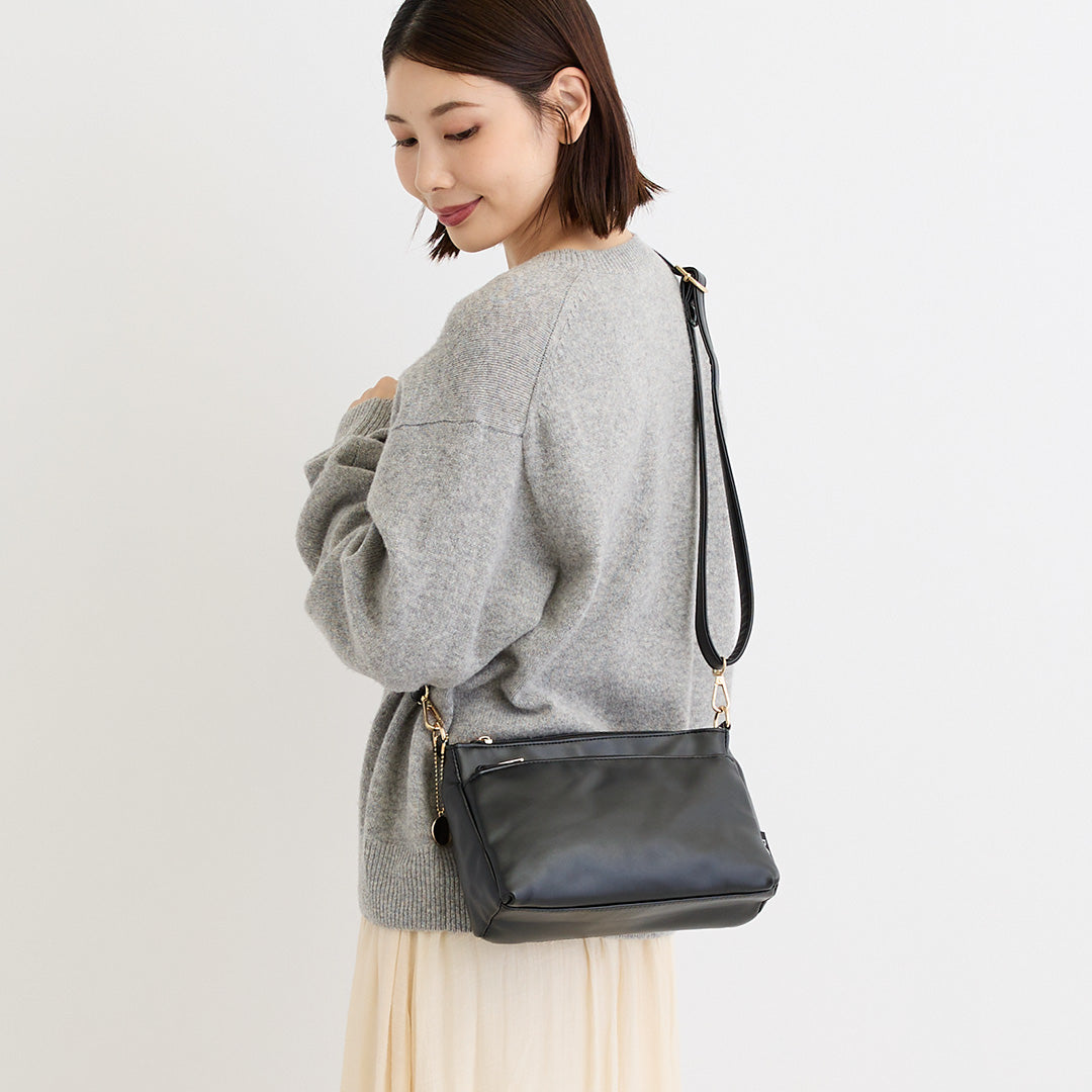 ブラック合皮ショルダーバッグを肩掛けする女性