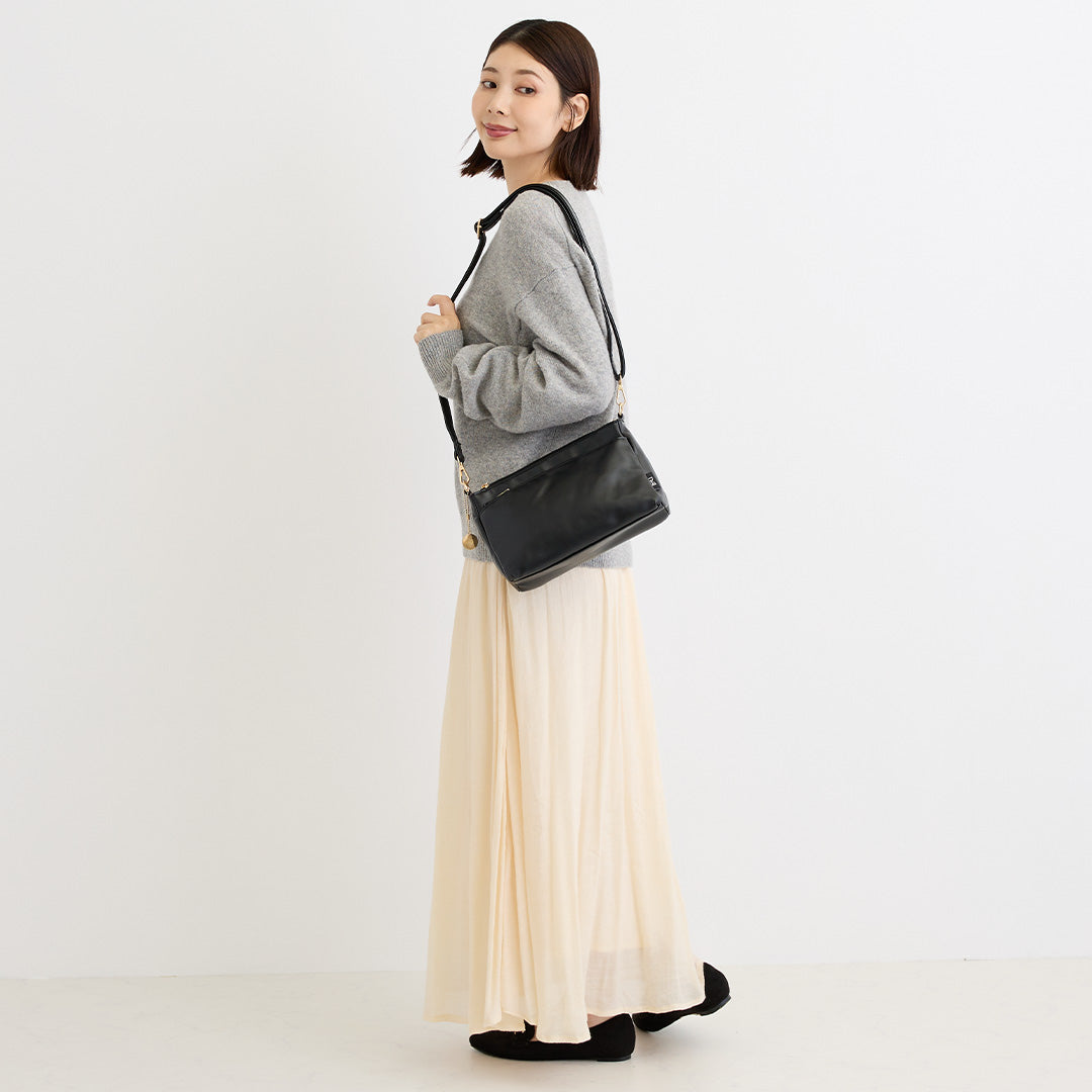 ブラック合皮ショルダーバッグを肩掛けした女性