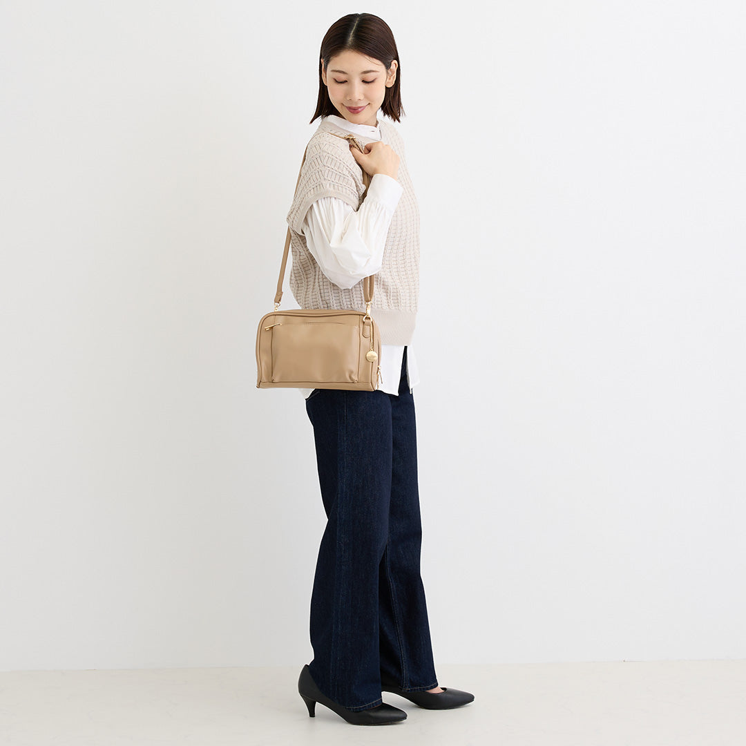 ベージュの合皮ショルダーバッグを肩掛けした女性